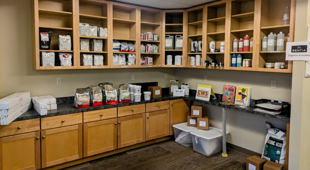 Open cupboards and a countertop filled with winemaking supplies for sale.